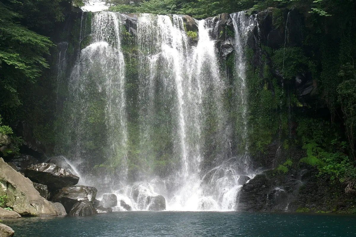 A waterfall pouring into a dark pool on Jeju